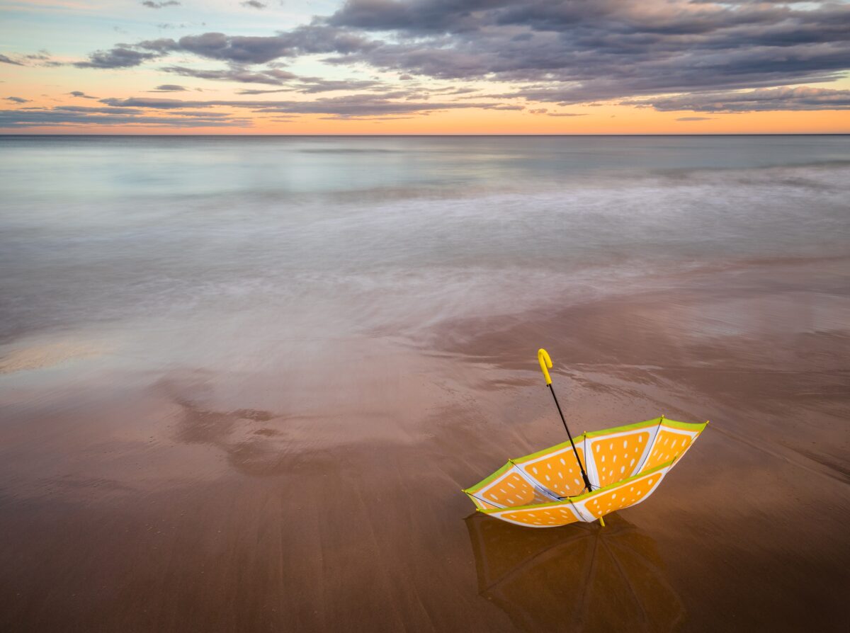 Upside-down umbrella colored like orange slices lying on a beach